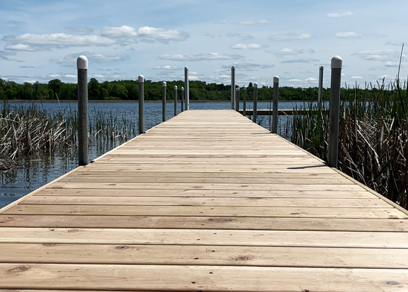 Wood lake dock extending into calm water in West Central Minnesota.